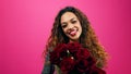 Beautiful multi-ethnic woman holds bunch of red roses, romance, pink studio