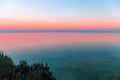 Beautiful multicolor sunset reflected in the waters of Lake Garda, Italy. Skyline. Visible coastline in the evening fog. Winter