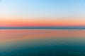 Beautiful multicolor sunset reflected in the waters of Lake Garda, Italy. Skyline. Visible coastline in the evening fog. Winter Royalty Free Stock Photo