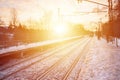 Beautiful multicolored cloudy sky during a bright orange sunset. Track passes through the village plantations. Russian railway la