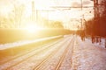 Beautiful multicolored cloudy sky during a bright orange sunset. Track passes through the village plantations. Russian railway la