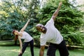 Beautiful multiethnic couple in sports clothes is stretching on yoga mats while working out outdoors at city park Royalty Free Stock Photo