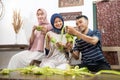 muslim family and friend making ketupat for eid fitr mubarak