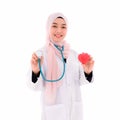 Beautiful muslim female doctor wearing hijab standing holding stethoscope and red heart Royalty Free Stock Photo