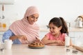 Beautiful Muslim Mother And Cute Little Daughter Cutting Homemade Pie In Kitchen Royalty Free Stock Photo