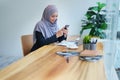 Beautiful Muslim woma talking on the phone and using a computer on her desk