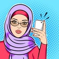 Beautiful muslim woman in hijab holding mobile phone reading sms or taking selfie concept vector in pop art comic retro style Royalty Free Stock Photo