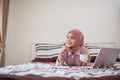 beautiful Muslim woman lying down and holding a coffee cup in bed Royalty Free Stock Photo