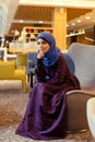 Beautiful muslim woman in modern oriental clothes sitting in a chair in the lobby Royalty Free Stock Photo