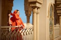 Beautiful Muslim woman standing between marble columns, looking into the distance, while wind blowing shawl on her head