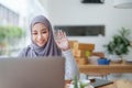 Beautiful Muslim woman using computer to greet attendees via video conference