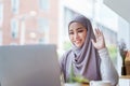 Beautiful Muslim woman using computer to greet attendees via video conference