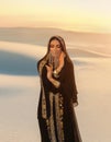 Beautiful mysterious arab woman Queen in black, muslim dress. head with silk handkerchief, golden chains hides face. A