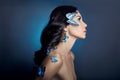 Beautiful mysterious woman with butterflies blue color on her face, brunette and paper artificial blue butterflies on the girls