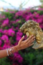 a beautiful nail polished female hand touches the garden statue. Fashion concept. Royalty Free Stock Photo