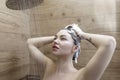 Beautiful naked young woman washes her hair and uses shampoo while taking a