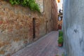 Beautiful narrow street with sunlight and flowers in the small magical and old village of Pienza, Val D`Orcia Tuscany.