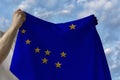 Beautiful national flag of alaska in male hands against the blue sky with clouds