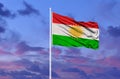 Beautiful national state flag of Kurdistan fluttering at sky background.