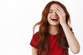 Beautiful natural girl with ginger curly, laughing sincere and smiling white teeth, covering half of face, standing in