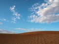 Beautiful natural pattern of rusty red desert sand dune with bright blue sky and white cloud background, Sossus, Namib Desert