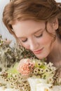 Beautiful natural redhead girl bride, with nude makeup, wearing a white dress, tenderly holds a wedding bouquet in her hands. Royalty Free Stock Photo