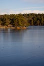 Beautiful natural Scandinavian landscape. Frozen lake with forest and stones at the shore line. Sunny late autumn or winter day in Royalty Free Stock Photo