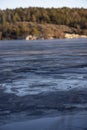 Beautiful natural Scandinavian landscape. Frozen lake with forest and stones at the shore line. Sunny late autumn or winter day in Royalty Free Stock Photo