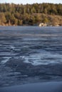 Beautiful natural Scandinavian landscape. Frozen lake with forest and stones at the shore line. Sunny late autumn or winter day in Royalty Free Stock Photo