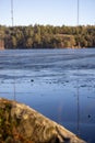 Beautiful natural Scandinavian landscape. Frozen lake with forest and stones at the shore line. Sunny late autumn or winter day in Royalty Free Stock Photo