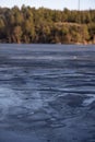 Beautiful natural Scandinavian landscape. Frozen lake with forest and stones at the shore line. Sunny late autumn or winter day in Royalty Free Stock Photo