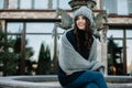 Beautiful natural young smiling brunette woman wearing knitted sweater, leather gloves, scarf and hat. Covered with snow flakes.