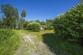 Beautiful nature landscape on sunny summer day. Small wooden private house between tall green trees on blue sky background