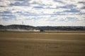 Beautiful nature landscape view. Combine machine on a wheat field of field after harvesting under cloudy summer sky.