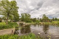 Beautiful nature landscape view. Small wooden bridge over pond and village houses between green trees. Royalty Free Stock Photo