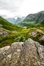 Path over green pasture in the mountains of Western Norway with snow on the summits and a dark cloudy sky Royalty Free Stock Photo