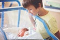 Beautiful newborn baby boy, laying in crib in prenatal hospital, his brothers looking at him Royalty Free Stock Photo