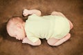 Beautiful newborn baby boy sleeping peacefully on the soft brown blanket