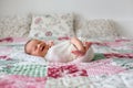 Beautiful newborn baby boy, widely smiling, wrapped in wrap, lying down in bed Royalty Free Stock Photo