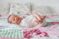 Beautiful newborn baby boy, widely smiling, wrapped in wrap, lying down in bed Royalty Free Stock Photo