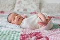 Beautiful newborn baby boy, widely smiling, wrapped in wrap, lying down in bed Royalty Free Stock Photo