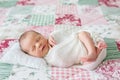 Beautiful newborn baby boy, widely smiling, wrapped in wrap, lying down in bed Royalty Free Stock Photo