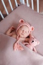 Beautiful newborn baby girl wearing pink hat and peacefully sleeping in her bed. Royalty Free Stock Photo