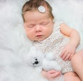Beautiful newborn girl sleeping on fluffy plaid with toy