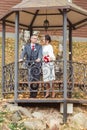 Beautiful newlyweds in love are standing in an autumn gazebo. Wedding Concept