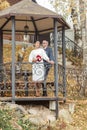 Beautiful newlyweds in love are standing in an autumn gazebo. Wedding Concept