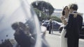 Beautiful newlyweds in reflection of car. Action. Newlyweds are hugging on city street with reflection in car windows Royalty Free Stock Photo