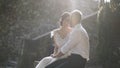 Beautiful newlyweds sitting in sunlight. Action. Beautiful bride and groom sit and look at each other illuminated by