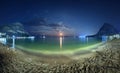 Beautiful night landscape at the seashore with yellow sand, full moon, mountains and lunar path. Moonrise. Vacations on the beach