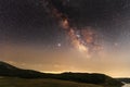 Beautiful night landscape, starry sky with bright milky way galaxy above the mountains with green field and lake. Astronomical bac Royalty Free Stock Photo